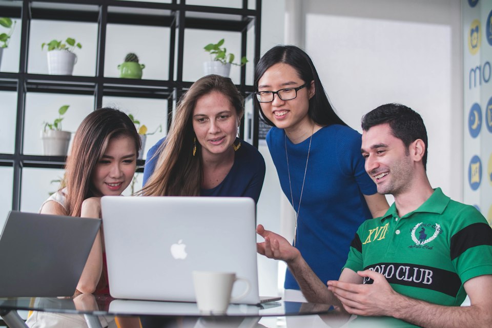 Four colleagues learning together around a laptop