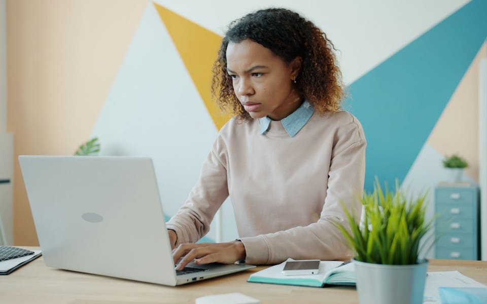 A woman concentrating on her laptop at a desk in a bright office