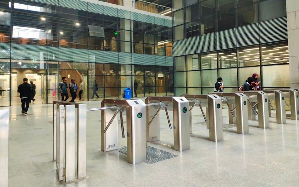 People walking through the security gates of an office lobby