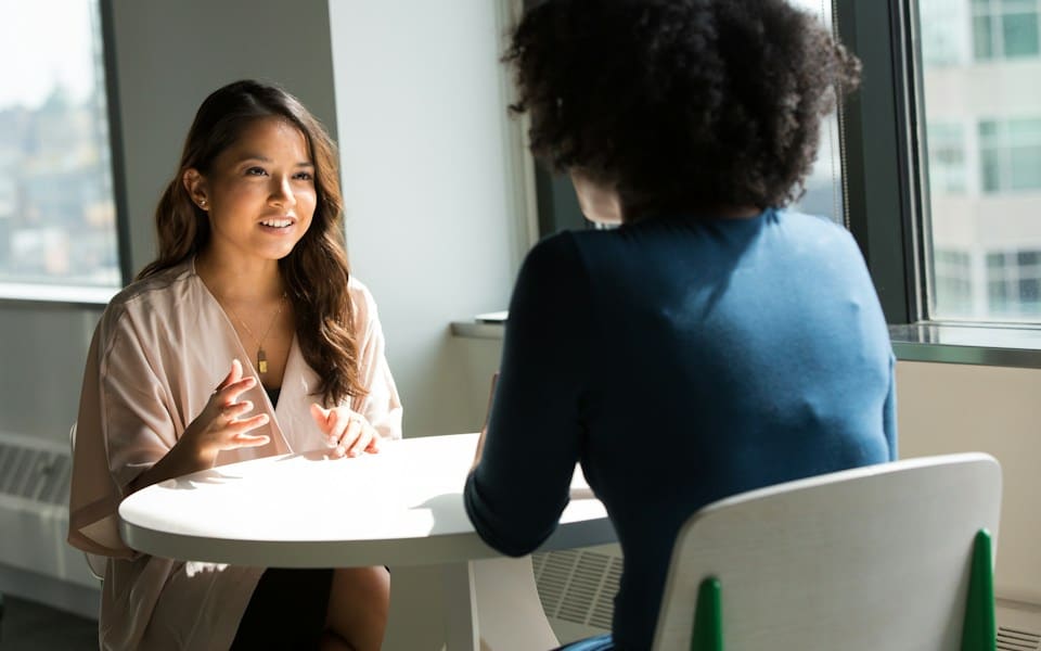 A woman speaking with a colleague at a small round table